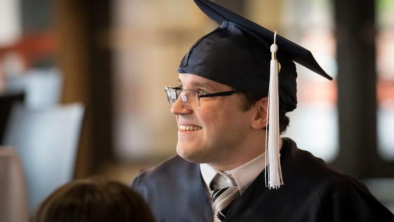 man with graduation cap on looking off into distance