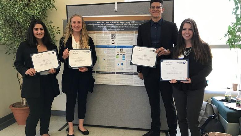 Four students posing in front of research poster