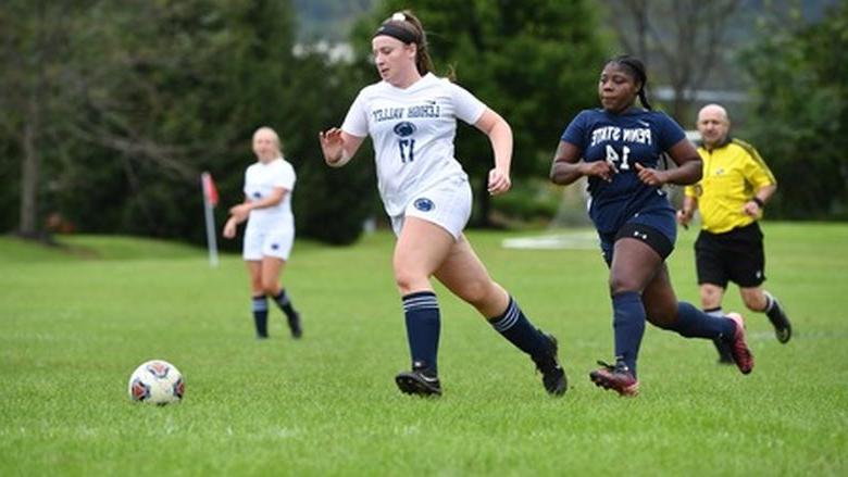 woman dribbling soccer ball down field